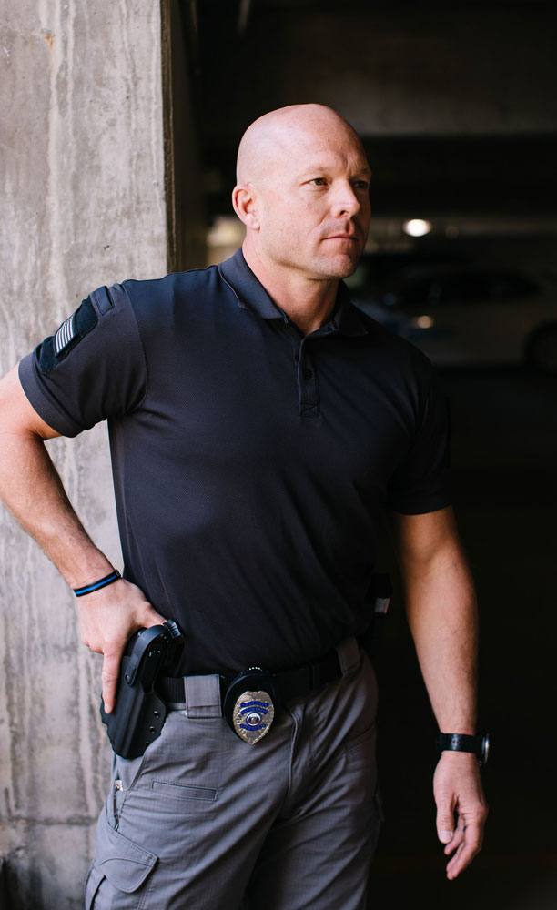 Security guard standing with hand on holstered pistol