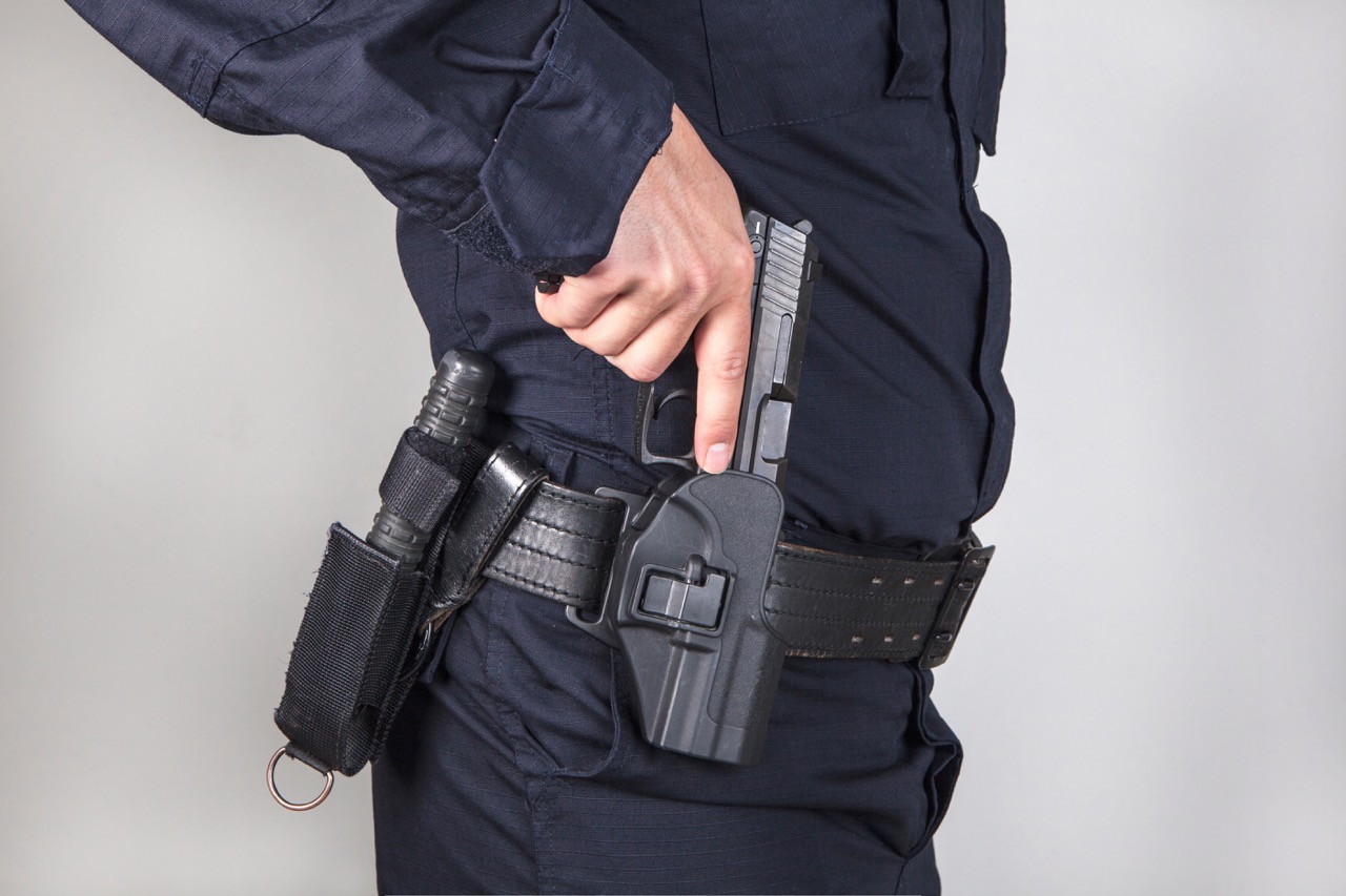 armed security guard unholstering pistol